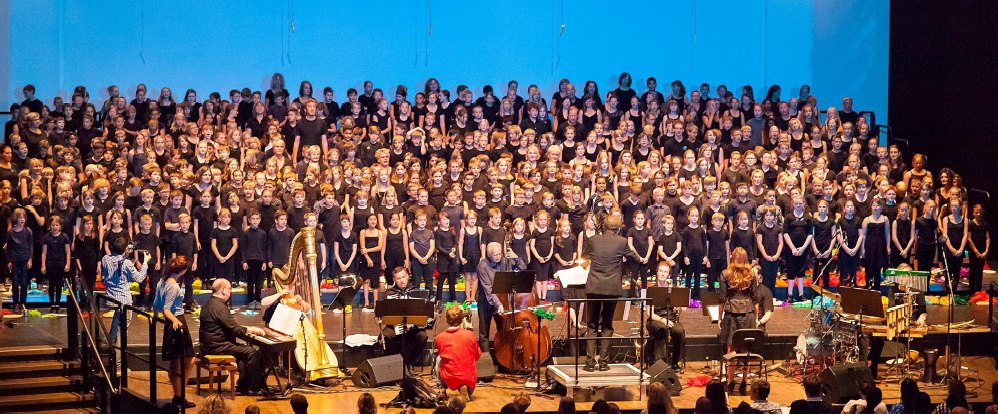 Großer Kinderchor mit Orchester auf einer Konzertbühne