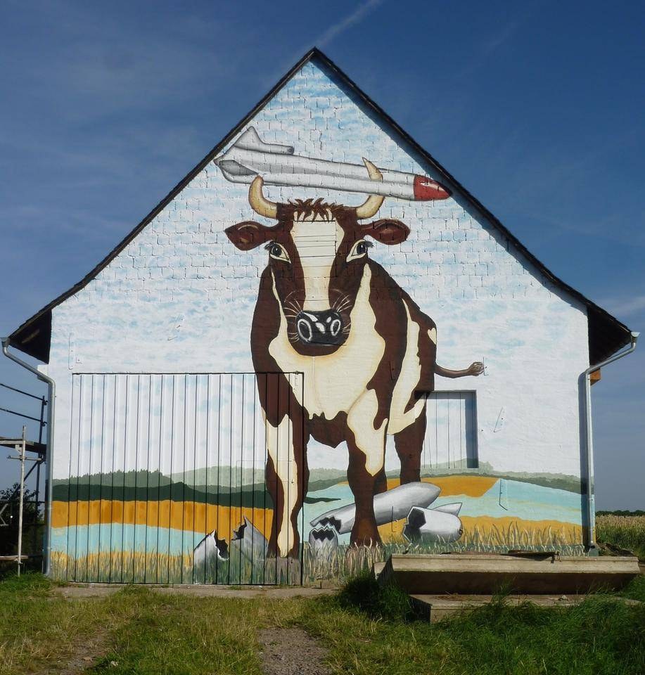 Der frisch restaurierte Giebel der Scheune in Bell: eine Kuh nimmt eine Rakete auf die Hörner, im Gras liegen zerbrochene Marschflugkörper