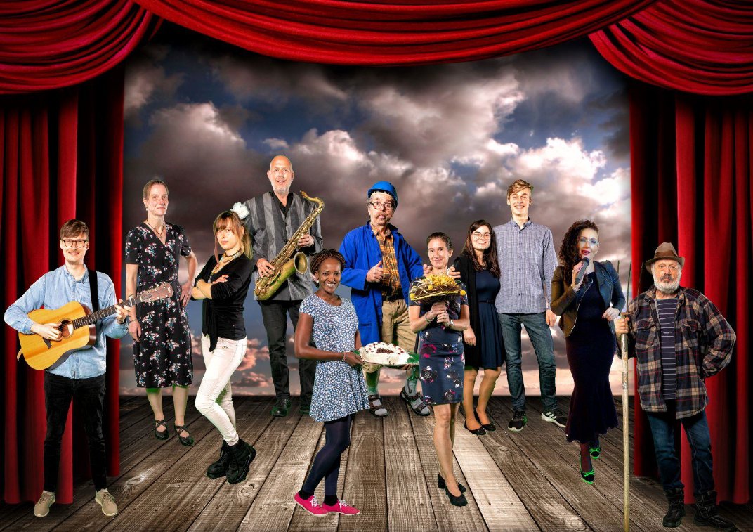 Ensemble des Musiktheaterprojekts SIMMERSTEIN auf einer Bühne mit rotem Vorhang